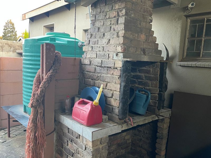 Outdoor brick braai area featuring a built-in chimney and adjacent water storage tank located in the rear yard.