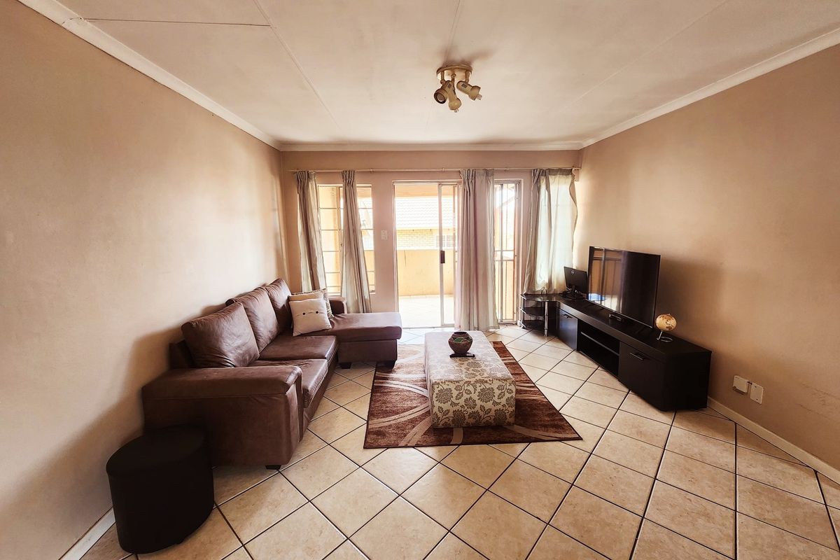 A living room featuring tiled flooring, a coved ceiling, and a sliding glass door providing access to an outdoor area.