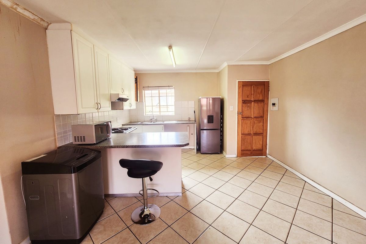 Functional kitchen featuring built-in cabinetry, tiled flooring, and a breakfast counter, offering a practical layout with potential for cosmetic updates.