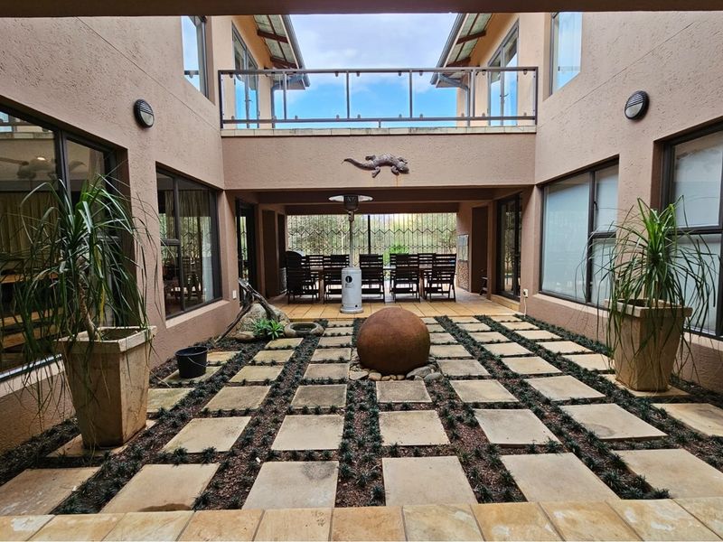 A central courtyard featuring paved walkways, landscaped garden beds, and a covered patio area, providing a seamless transition between indoor and outdoor living spaces.