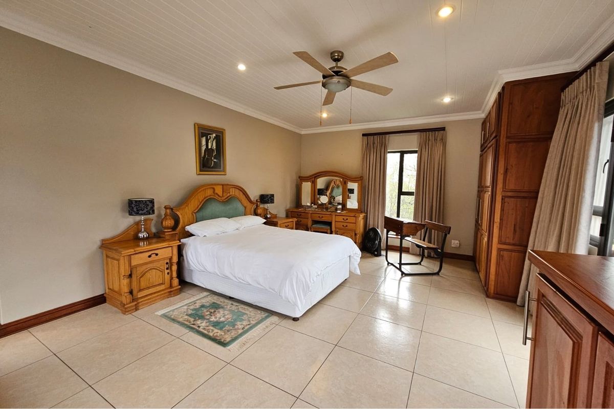 Spacious bedroom featuring tiled flooring, a ceiling fan, and built-in wooden cabinetry.