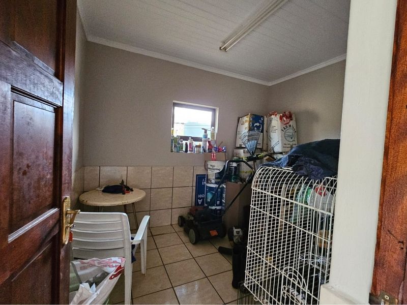 A utility space featuring tiled flooring and walls, suitable for storage or laundry use, providing functional space for household maintenance.
