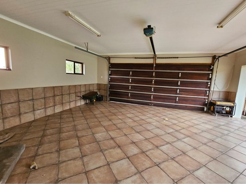Spacious double garage featuring tiled flooring, half-tiled walls, and an automated wooden sectional garage door.