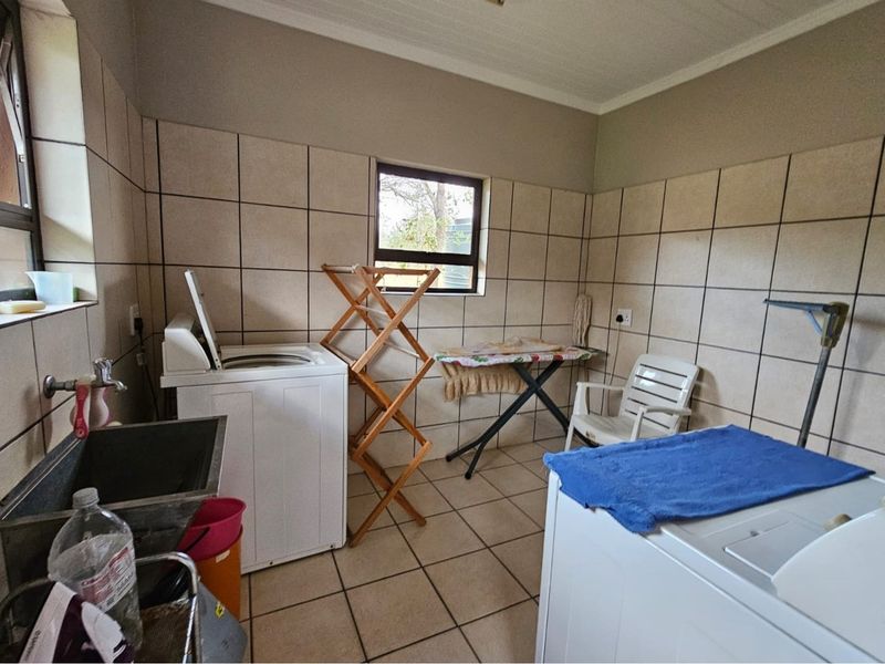 A functional laundry room featuring tiled walls and flooring, a built-in utility sink, and dedicated space for laundry appliances.