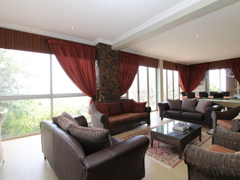 Spacious living area featuring large glass sliding doors, stone-clad architectural pillars, recessed lighting, and neutral tiled flooring with abundant natural light.