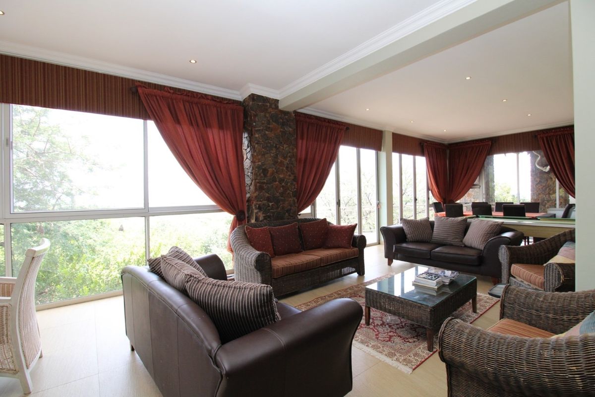 Spacious living area featuring large glass sliding doors, stone-clad architectural pillars, recessed lighting, and neutral tiled flooring with abundant natural light.