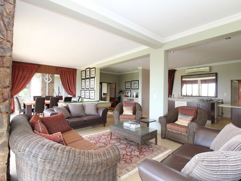 Spacious open-plan living area featuring a stone accent wall, crown molding, recessed lighting, and a built-in bar area.