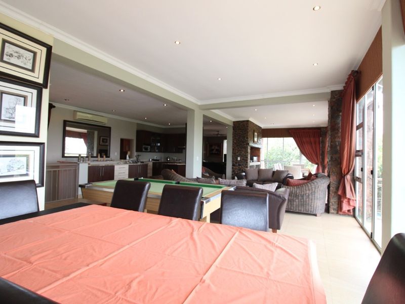Spacious open-plan living and dining area featuring tiled floors, recessed lighting, and a stone feature wall with seamless access to the outdoors.