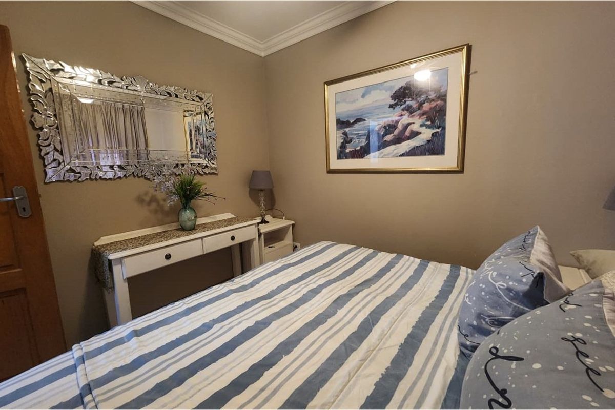 A cozy bedroom featuring neutral wall tones, crown molding, and a classic layout suitable for a comfortable sleeping space.