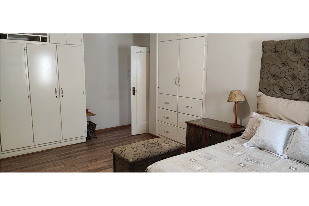 A bedroom featuring built-in cabinetry with ample storage, wood-look flooring, and a neutral color palette.