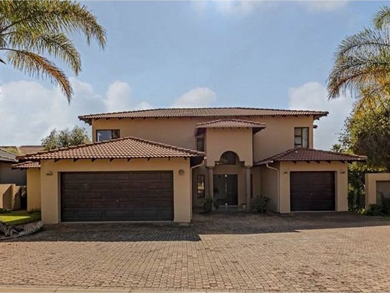 A well-maintained double-story residential home featuring a tiled roof, double garage, and a spacious paved driveway.