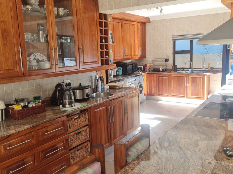 A spacious kitchen featuring extensive wooden cabinetry, granite countertops, a tiled backsplash, and integrated appliances, offering a functional and traditional cooking space.