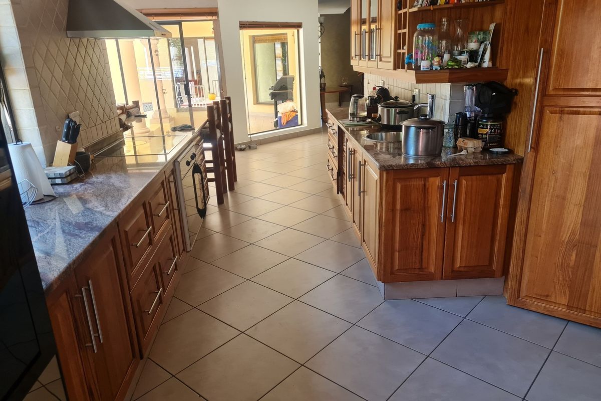 A functional kitchen featuring warm wooden cabinetry, granite countertops, and tiled flooring, with a direct view through to the outdoor patio area.
