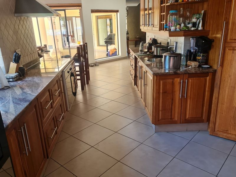 A functional kitchen featuring warm wooden cabinetry, granite countertops, and tiled flooring, with a direct view through to the outdoor patio area.