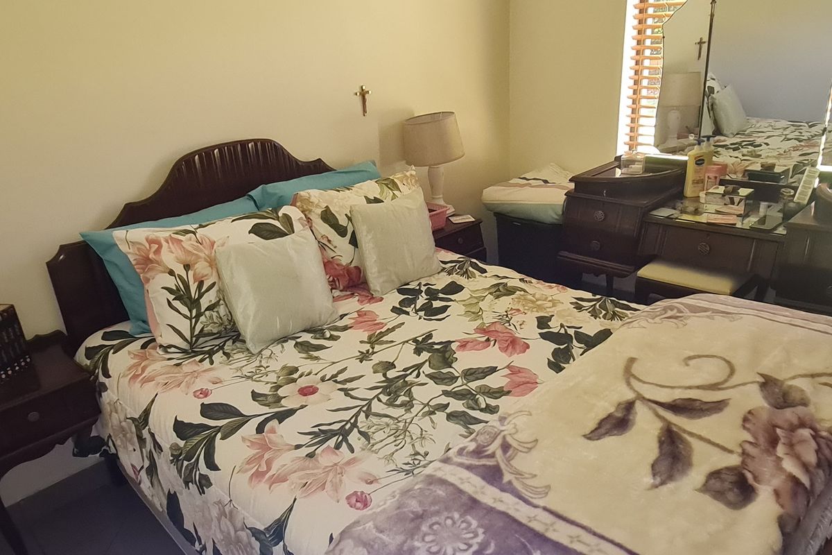 A bedroom featuring neutral wall finishes and venetian blinds, providing a functional and comfortable sleeping space.