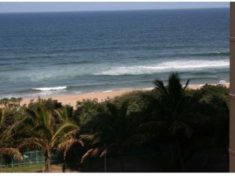 A scenic elevated view of the ocean and sandy beach, captured from the apartment balcony.