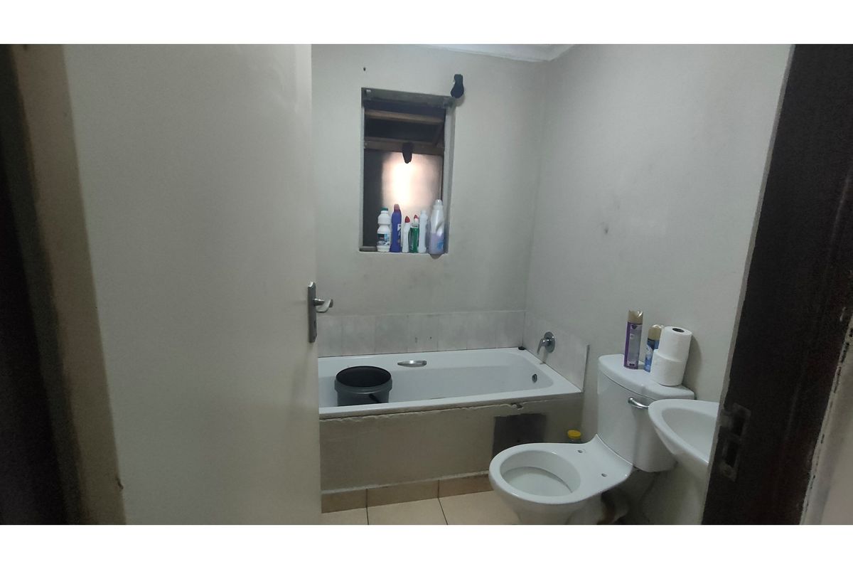 A functional bathroom featuring a standard bathtub, toilet, and basin, requiring cosmetic updates to improve the overall finish and aesthetic appeal.