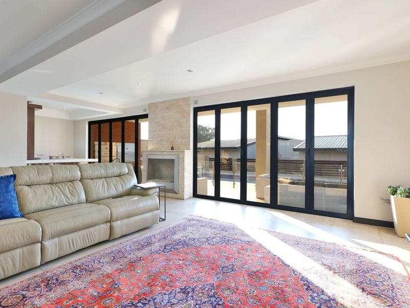 Spacious open-plan living area featuring a stone-clad fireplace and large black aluminium stacker doors providing seamless access to the outdoor patio.