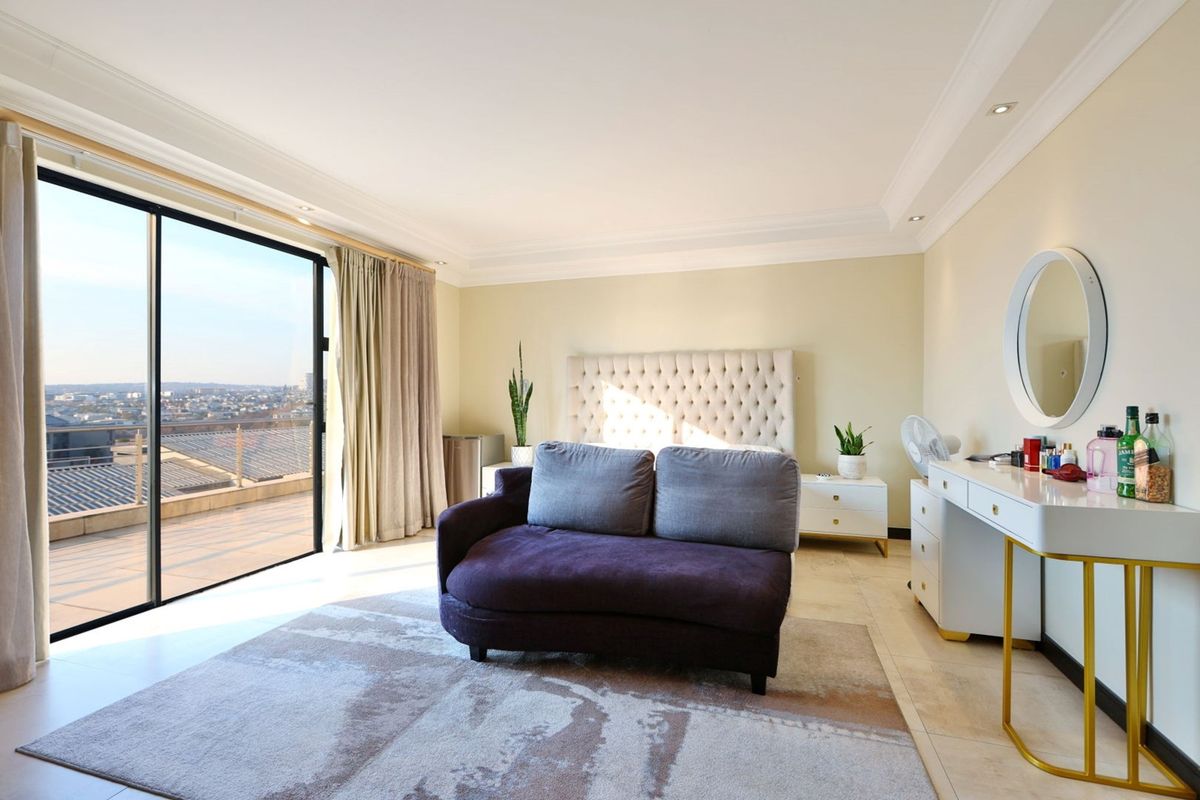 Spacious bedroom featuring large sliding glass doors leading to a balcony, recessed lighting, crown molding, and neutral tiled flooring.