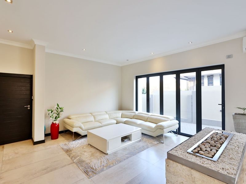 Modern living room featuring tiled floors, recessed lighting, a stone-clad fireplace, and large bi-fold doors providing seamless access to the outdoor area.
