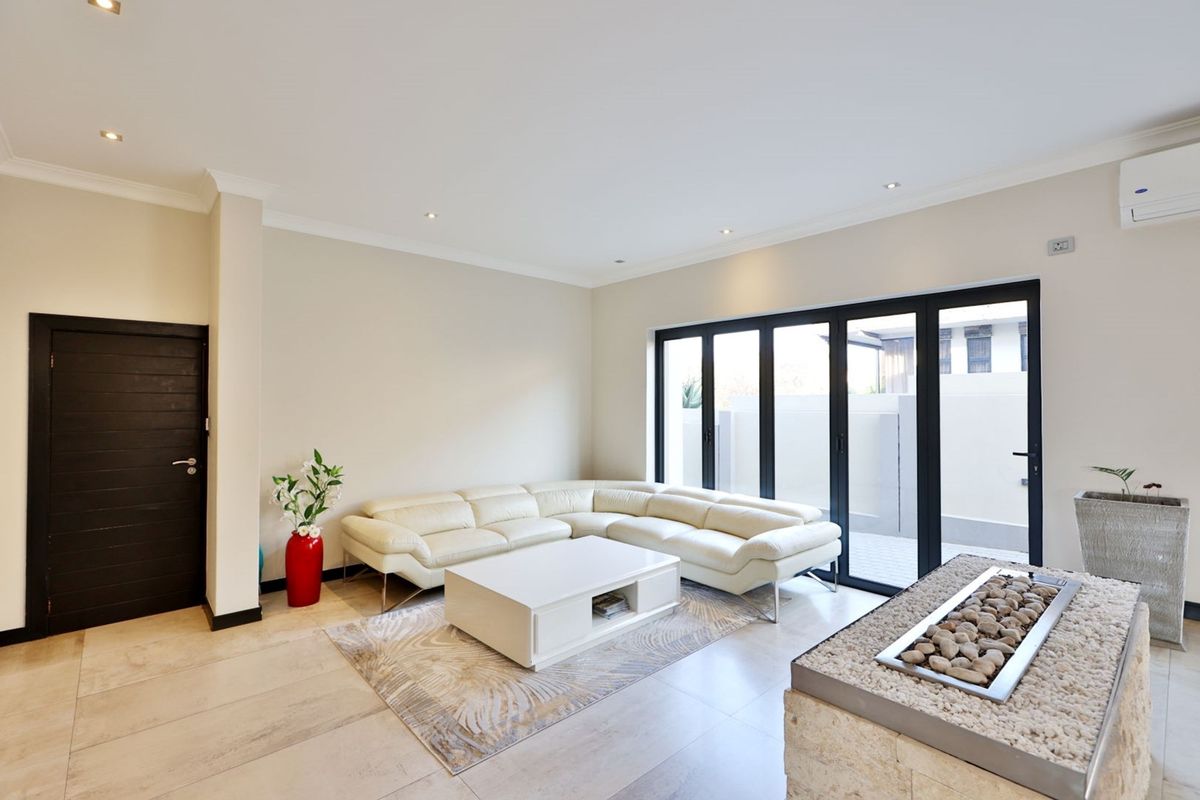 Modern living room featuring tiled floors, recessed lighting, a stone-clad fireplace, and large bi-fold doors providing seamless access to the outdoor area.