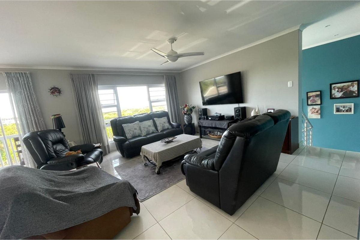 Spacious living room featuring neutral tiled flooring, a ceiling fan, and large windows providing natural light.