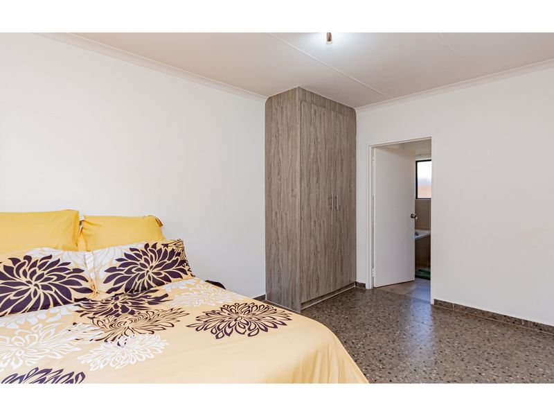 A bedroom featuring terrazzo flooring, a built-in wardrobe, and direct access to an en-suite bathroom.