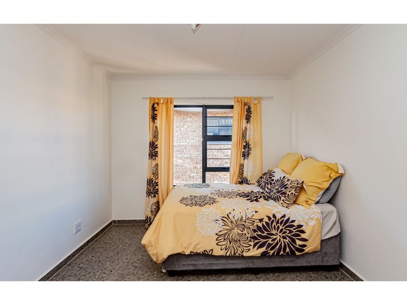 A bedroom featuring terrazzo flooring, coved ceilings, and an aluminium-framed window.