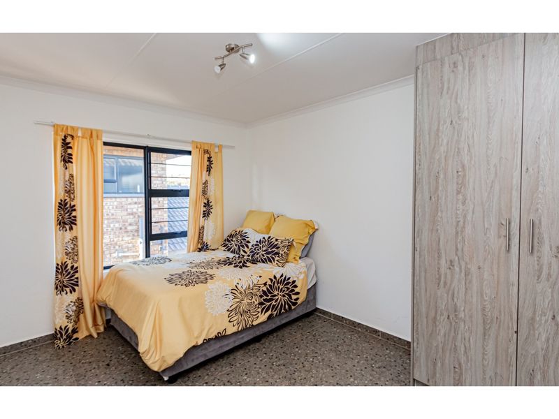 A bedroom featuring terrazzo flooring, a built-in wardrobe, and an aluminium window frame, providing a functional and well-lit living space.