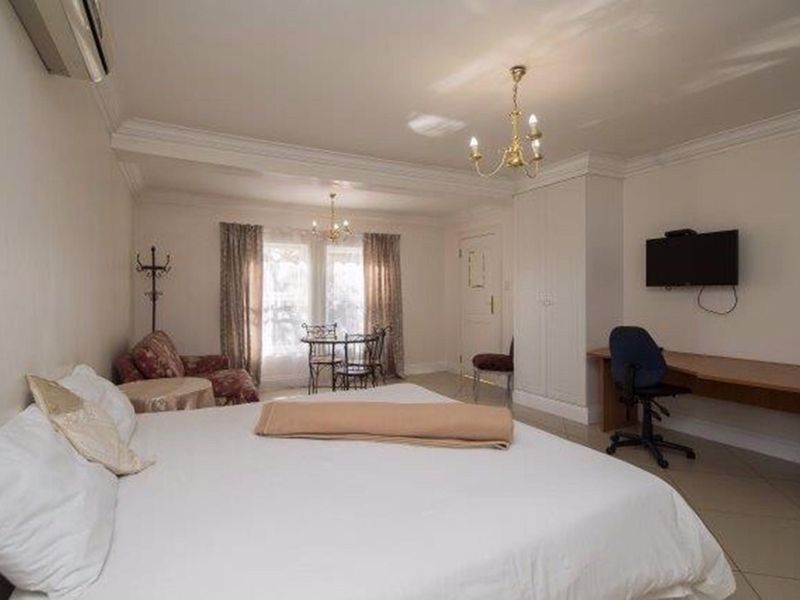 Spacious bedroom featuring tiled flooring, built-in wardrobe storage, and an integrated air conditioning unit.