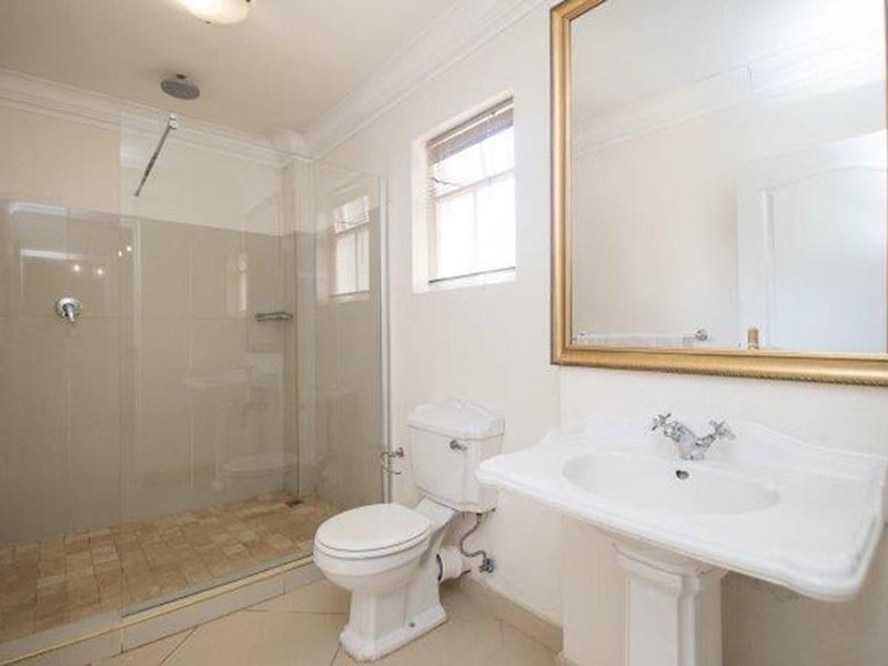 A clean and functional bathroom featuring a walk-in shower with a glass screen, a pedestal sink, and a toilet.