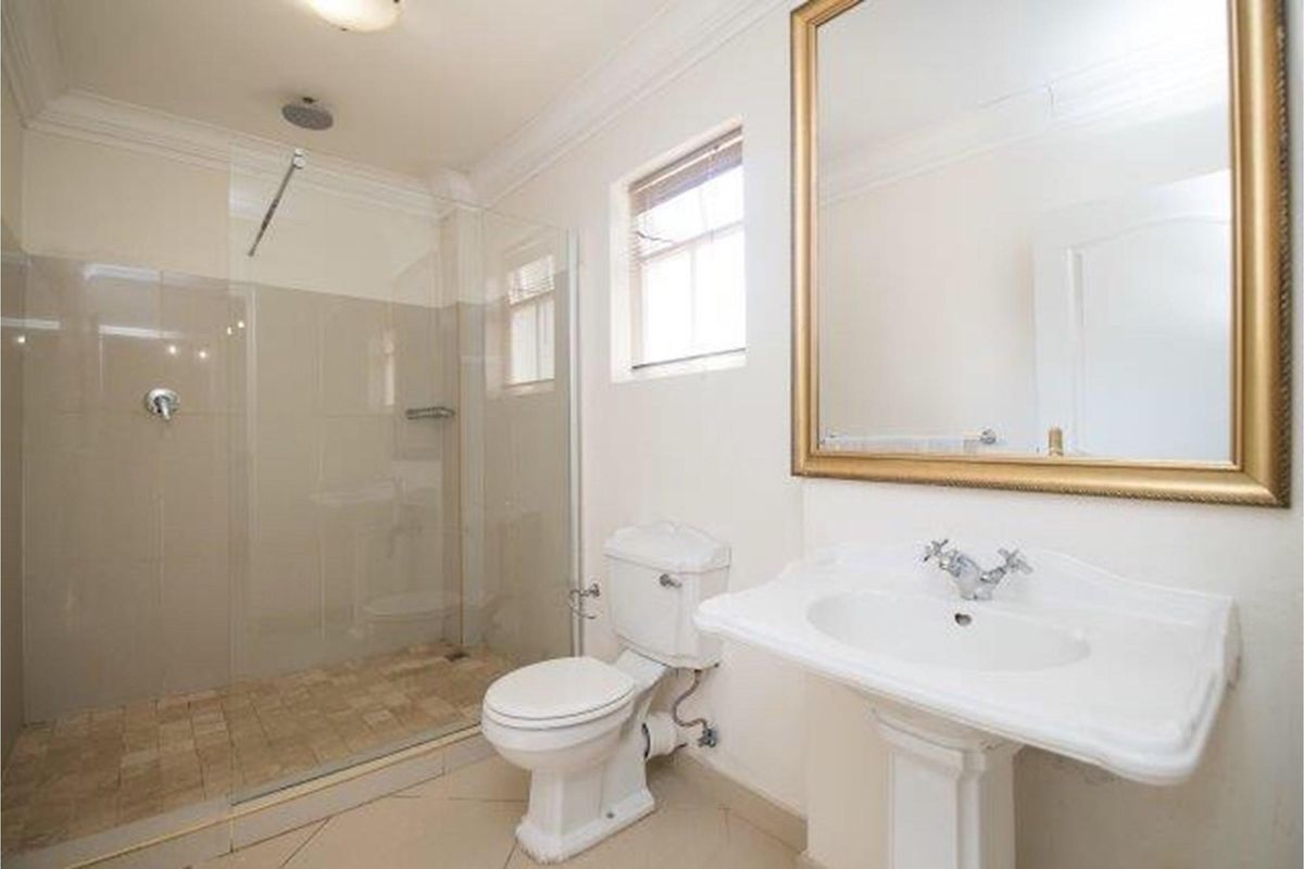 A clean and functional bathroom featuring a walk-in shower with a glass screen, a pedestal sink, and a toilet.