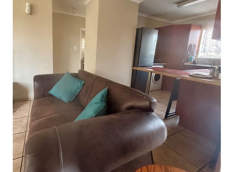 Open plan living and kitchen area featuring tiled flooring and a breakfast bar counter, providing a functional layout for daily living.