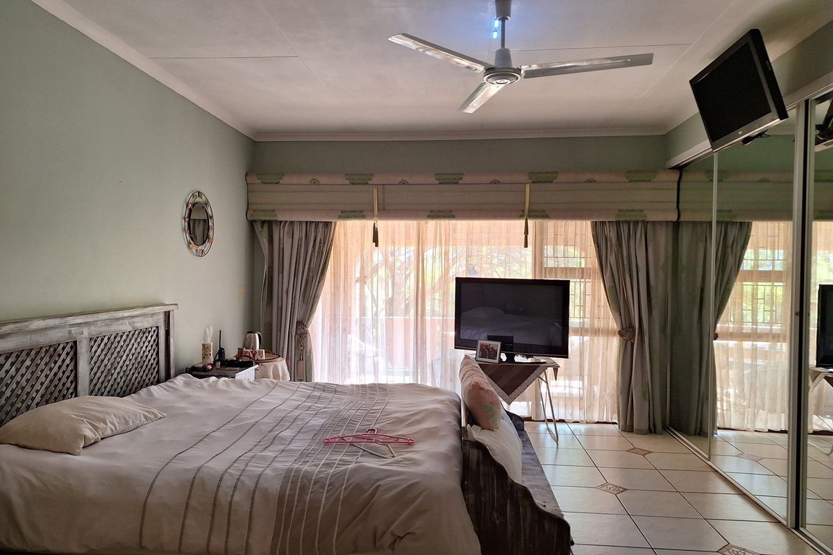 A spacious bedroom featuring tiled flooring, a ceiling fan, and large sliding glass doors with access to an outdoor area.