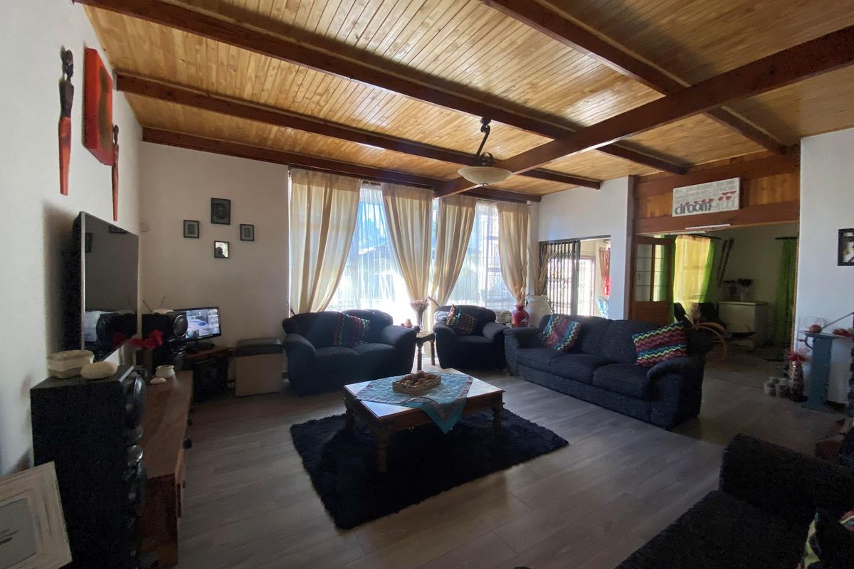 Spacious living room featuring a high timber-paneled vaulted ceiling with exposed beams and modern laminate flooring.