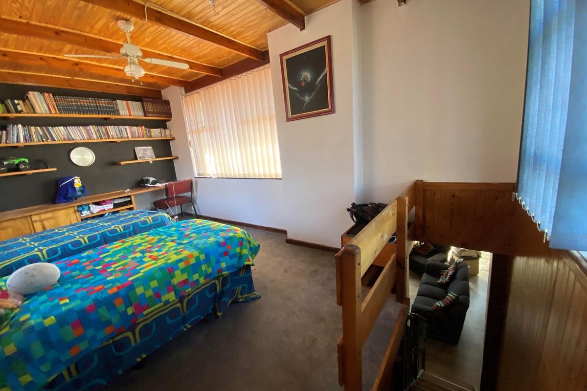 Spacious bedroom featuring a timber-beamed ceiling, built-in shelving, and an open mezzanine-style overlook to the lower level.