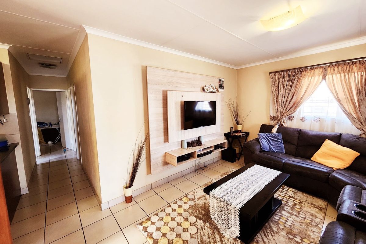 A living room featuring tiled flooring and a built-in media console unit, providing a functional space with neutral wall tones.