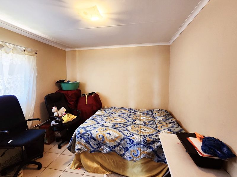 A standard bedroom featuring tiled flooring and coved ceiling details, providing a functional space ready for personalization.