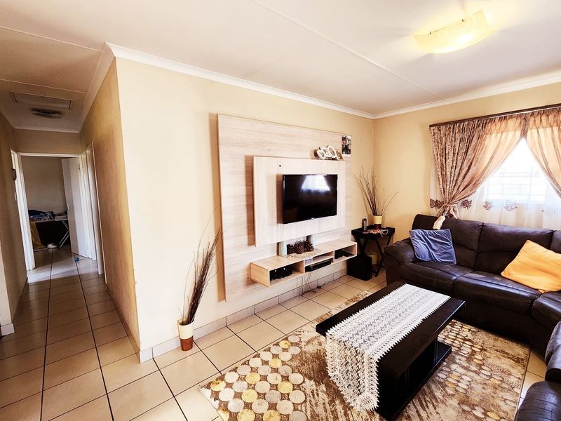 A living room featuring tiled flooring and a built-in media console unit, providing a functional space with neutral wall tones.