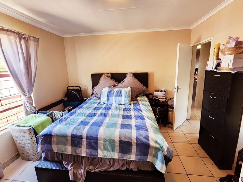 A standard bedroom featuring tiled flooring and coved ceiling details, providing a functional living space.