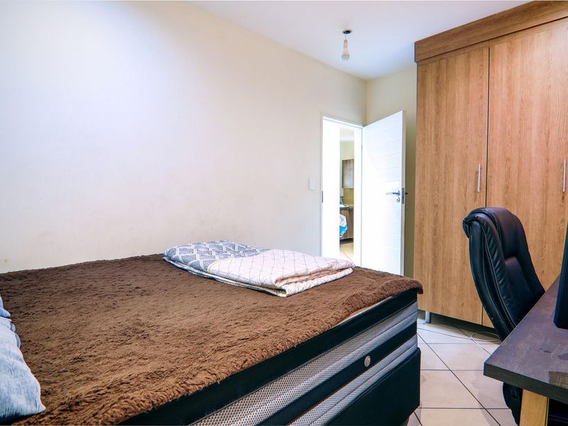 A bedroom featuring built-in wooden cabinetry and tiled flooring, with an open doorway leading to an adjacent room.