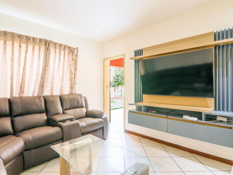 A living room featuring tiled flooring and a custom built-in media unit with integrated shelving and cabinetry.