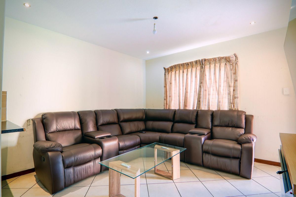 A living room featuring tiled flooring, recessed ceiling lighting, and a window with curtains.