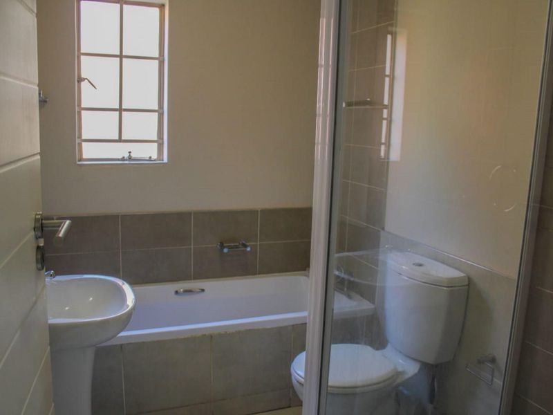 A functional bathroom featuring a pedestal basin, a built-in bathtub with tiled surround, and a separate glass-enclosed shower unit.