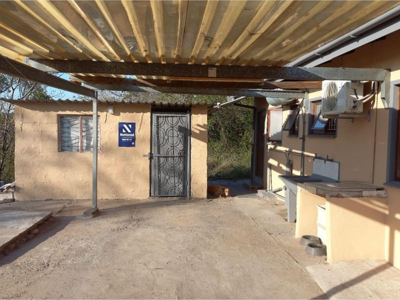 Covered outdoor utility area featuring a concrete floor, external sink, security gate, and corrugated metal roofing.