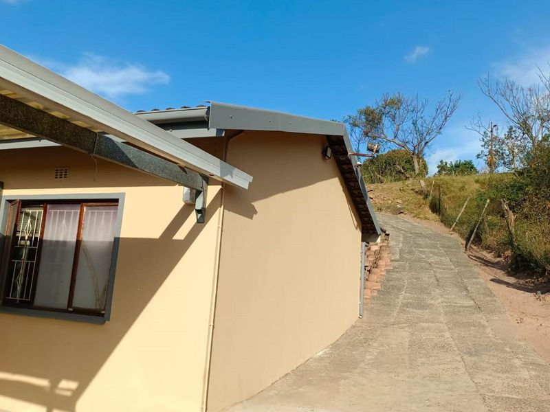 Exterior view of the rear property elevation featuring a concrete driveway and metal guttering system.