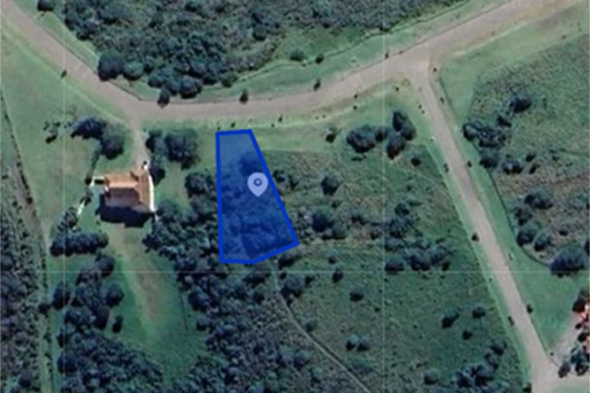 An aerial view of a vacant residential plot highlighted in blue, situated within a landscaped estate environment.