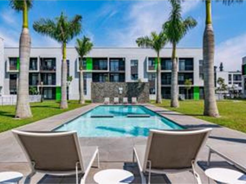 A well-maintained communal swimming pool area surrounded by landscaped gardens and modern apartment building facades.