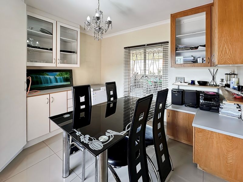 Dining area featuring tiled flooring, built-in cabinetry with glass-front display units, and a decorative chandelier.