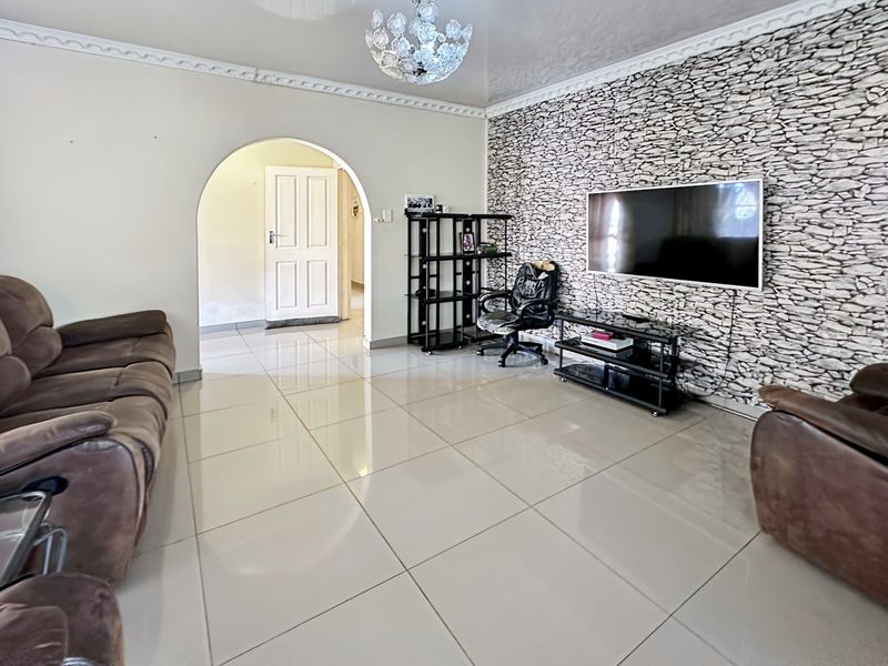 Spacious living room featuring polished porcelain floor tiles, decorative crown molding, and a textured stone-effect feature wall.